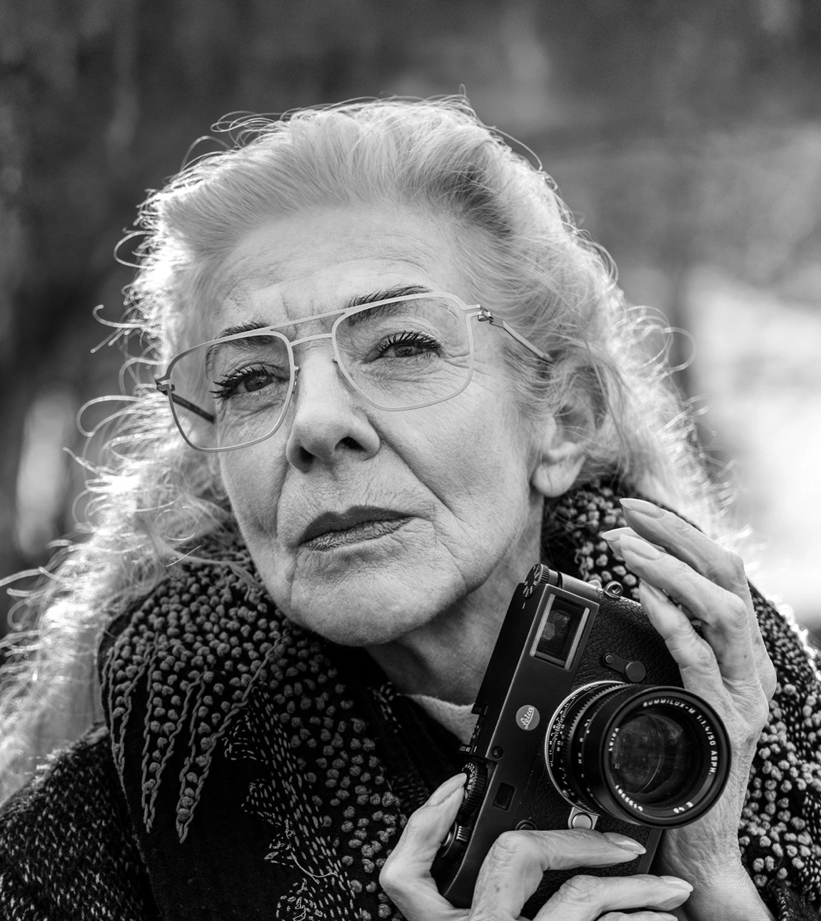 Femme portant des lunettes à verres premium de Leica avec un appareil photo à la main