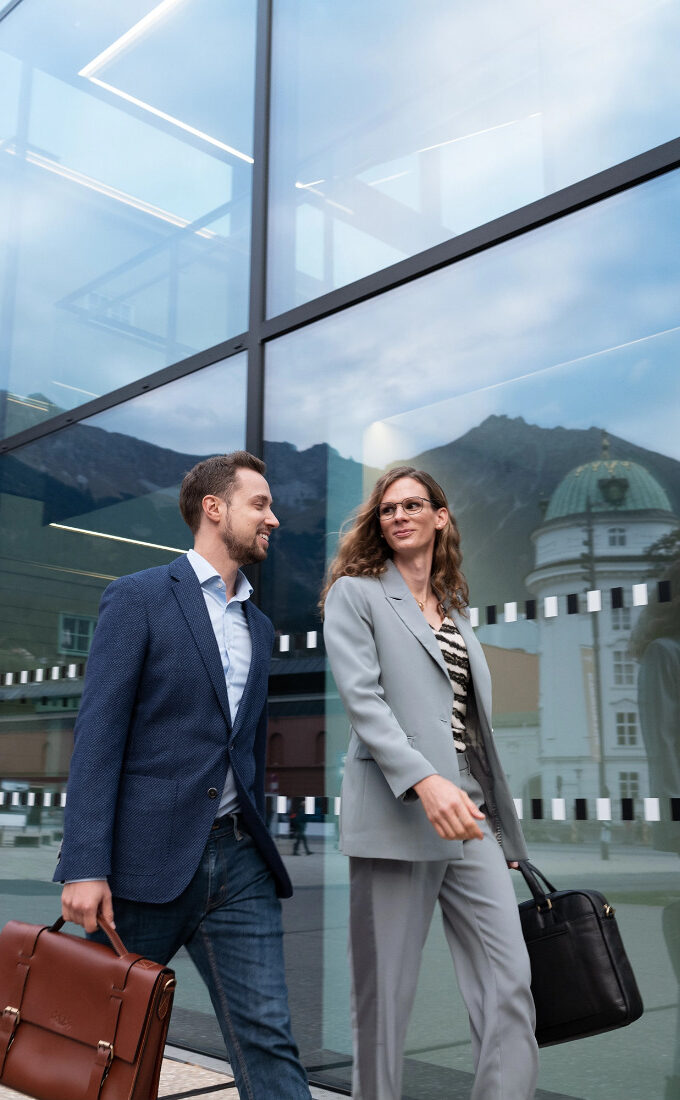 Frau mit Sonnenbrille mit Premium-Brillengläsern von Leica läuft gemeinsam mit einem Mann durch die Stadt