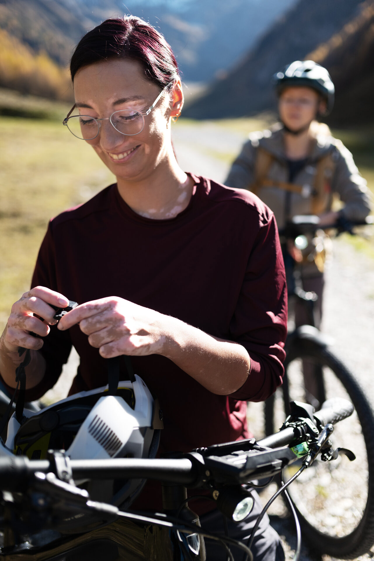 Junge Frau mit Brille mit Premium-Brillengläsern von Leica zieht einen Fahrradhelm auf